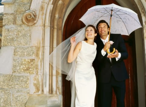 Married couple under umbrella at wedding