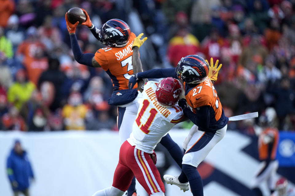 Denver Broncos safety Justin Simmons, left, intercepts a pass intended for Kansas City Chiefs wide receiver Marquez Valdes-Scantling (11) as Broncos cornerback Damarri Mathis (27) gets in on the play during the second half of an NFL football game Sunday, Oct. 29, 2023, in Denver. (AP Photo/David Zalubowski)
