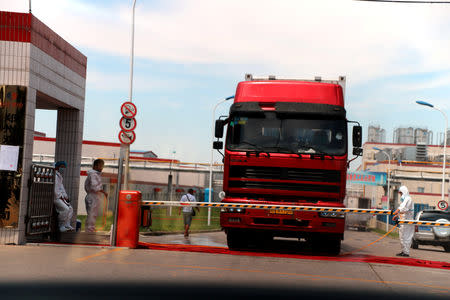 Workers in protective suits are seen by a truck at a plant of pork processor Henan Shuanghui Investment & Development, a subsidiary of WH Group, following a discovery of pigs infected by the African swine fever (ASF), in Zhengzhou, Henan August 17, 2018. Picture taken August 17, 2018 through a window. Wang Zhongju/CNS via REUTERS/File Photo