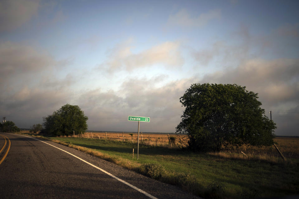 Morning sunlight is reflected off a road sign indicating the distance to Uvalde, Texas, on Saturday, May 28, 2022, in Texas. In a town as small as Uvalde, even those who didn't lose their own child lost someone at the fatal school shooting at Robb Elementary. Some say now that closeness is both their blessing and their curse: they can lean on each other to grieve. But every single one of them is grieving. (AP Photo/Wong Maye-E)