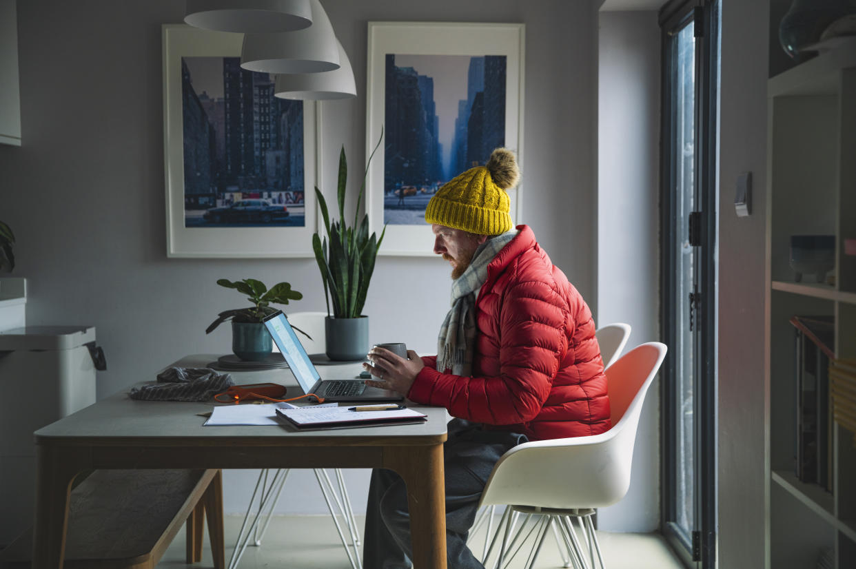 With the cost of energy soaring, a mature man resorts to outdoor winter clothing to stay warm rather than putting on the heating