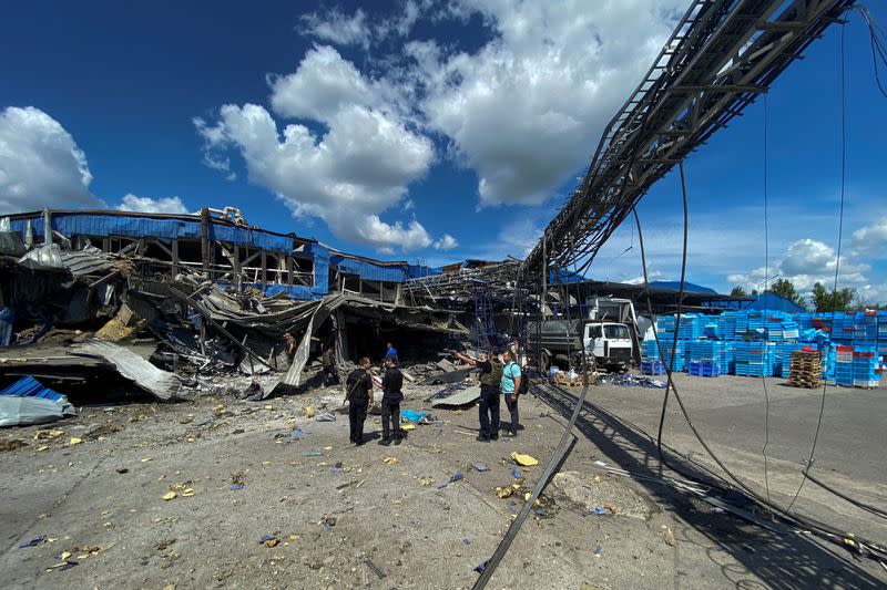 Personas en un lugar de las instalaciones de producción de alimentos destruidas por un ataque de misiles rusos en Járkov