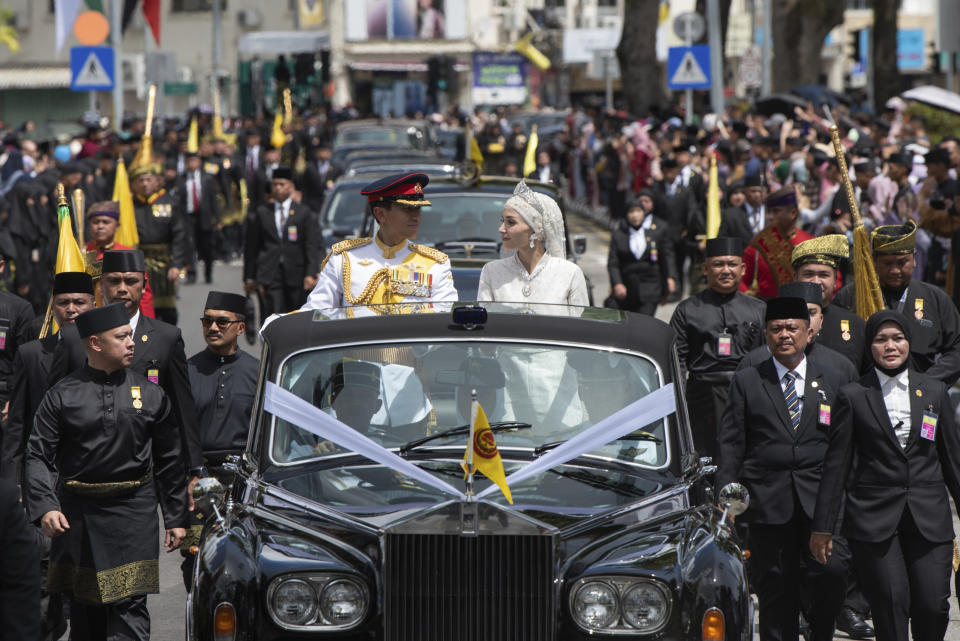 In this photo released by Brunei's Information Department, Brunei's Prince Abdul Mateen and bride Anisha Rosnah, in their car, attend the wedding procession in Bandar Seri Begawan, Brunei Sunday, Jan. 14, 2024. (Brunei's Information Department via AP)