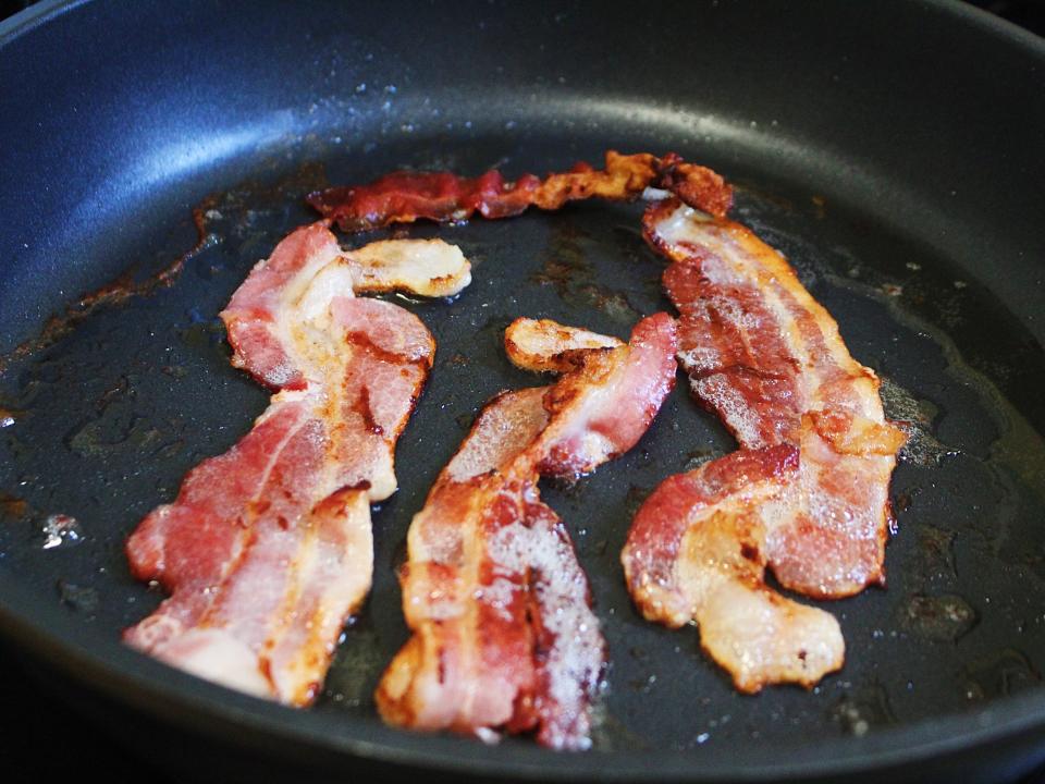 bacon frying in a pan on the stove