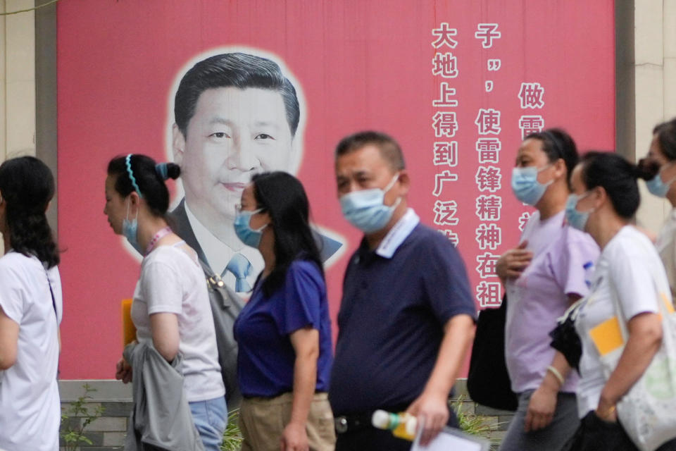 People wearing masks pass by portraits of Chinese President Xi Jinping, following the coronavirus disease (COVID-19) outbreak, in Shanghai, China, August 31, 2022. REUTERS/Aly Song