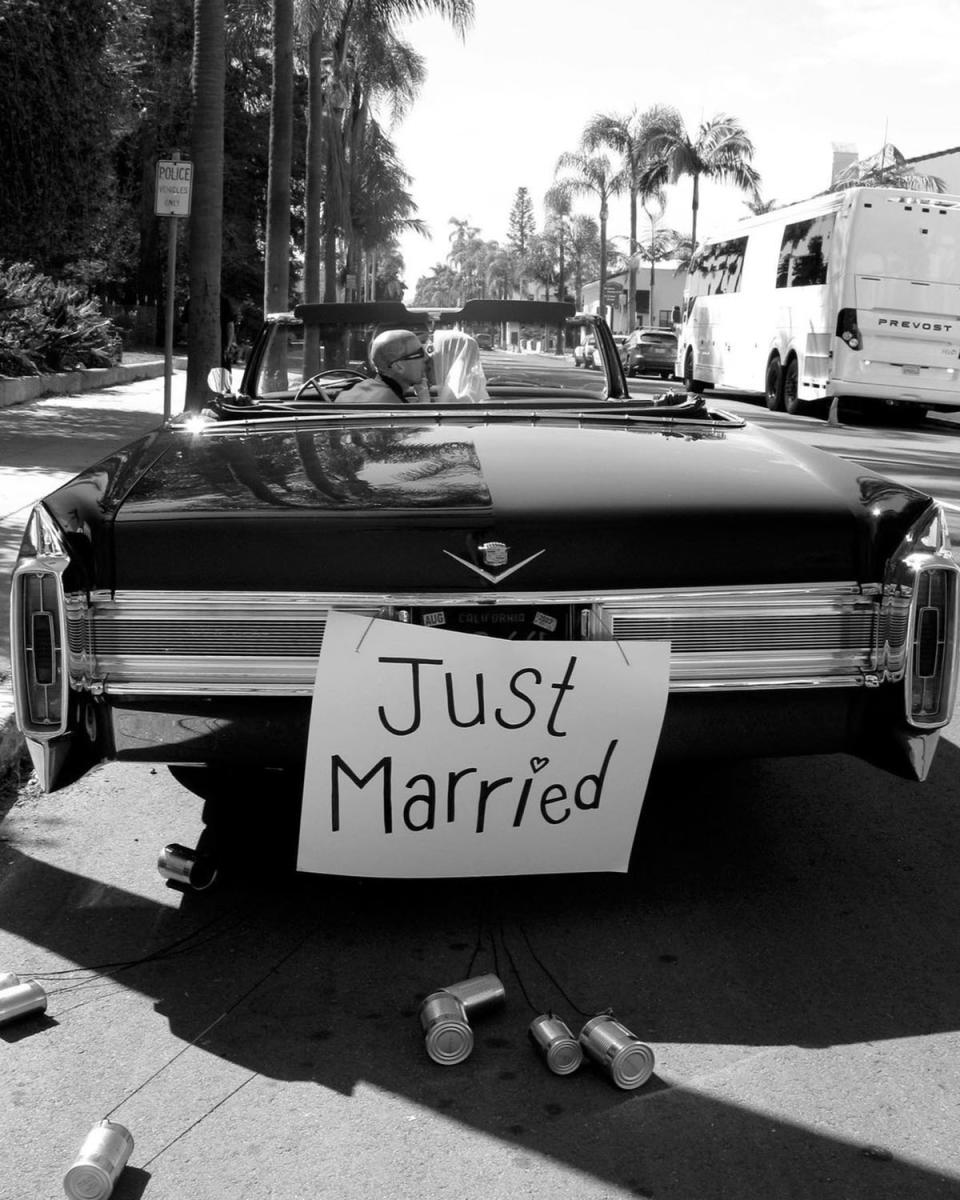 A car with 'Just Married' sign on the back, with Kourtney Kardashian and Travis Barker kissing in the front seat.