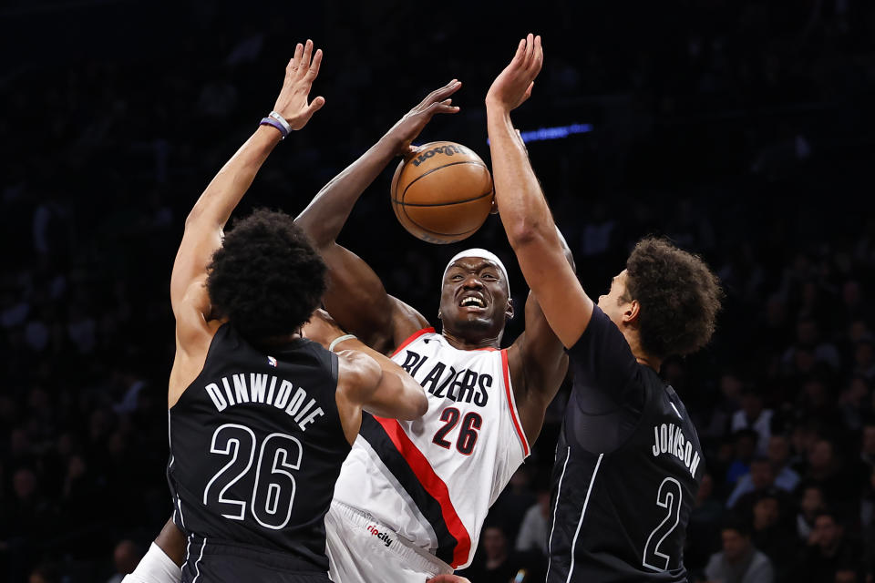 Portland Trail Blazers center Duop Reath, center, drives to the basket against Brooklyn Nets guard Spencer Dinwiddie, left, and forward Cameron Johnson (2) during the first half of an NBA basketball game, Sunday, Jan 7, 2024, in New York. (AP Photo/Noah K. Murray)