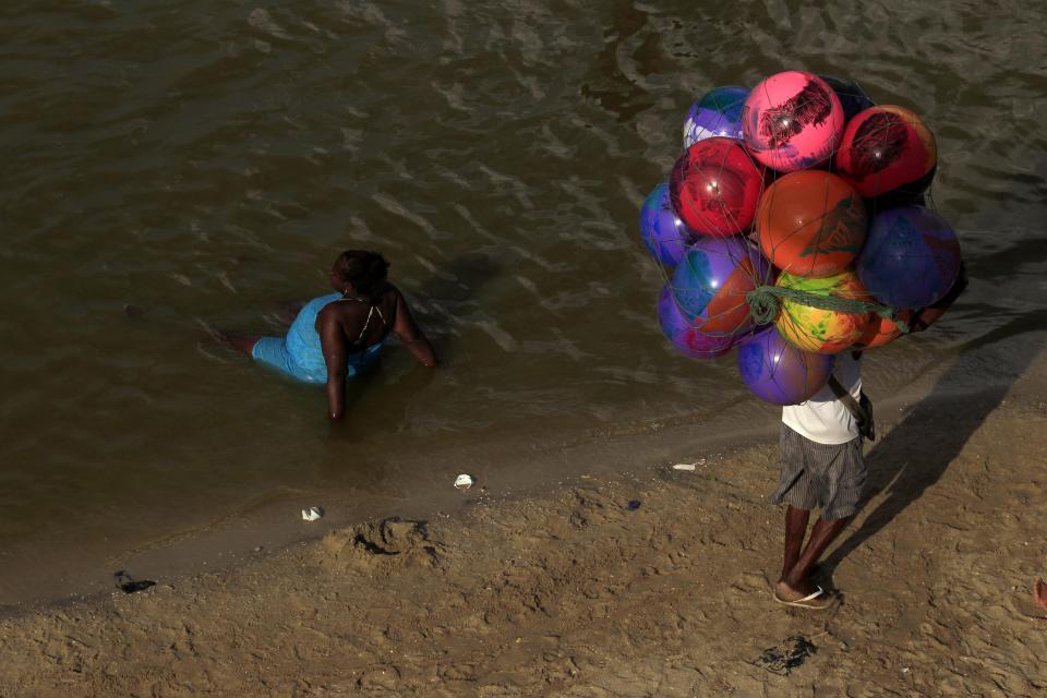 A vendor walks past a woman relaxing at the Piscinao de Ramos artificial lake in Rio de Janeiro