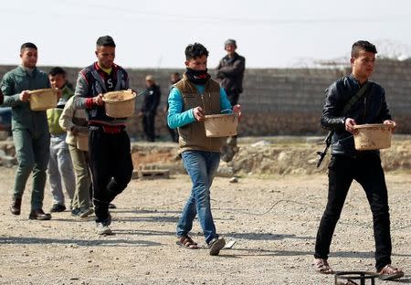 Sunni Arab fighters carries pots that are being made into improvised explosive devices (IEDs) to demolish homes belonging to Islamic State militants, in Rfaila village in the south of Mosul, Iraq, February 17, 2017. Picture taken February 17, 2017. REUTERS/Khalid al Mousily