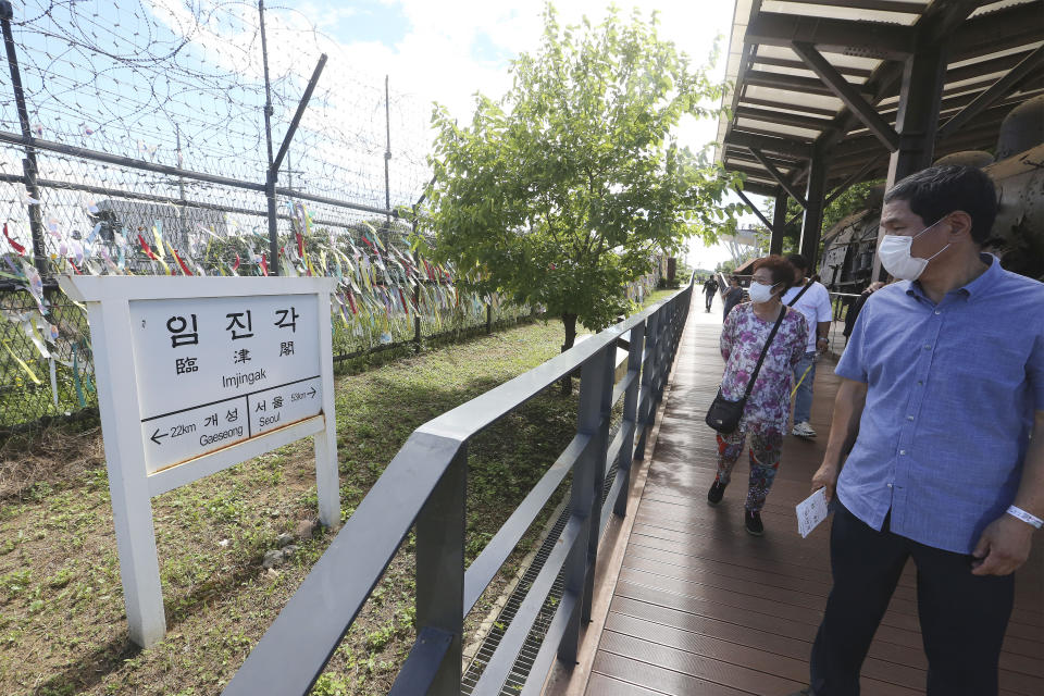 People wearing face masks to help protect against the spread of the new coronavirus pass by a directional sign showing the distance to North Korea's city Kaesong and South Korea's capital Seoul at the Imjingak Pavilion in Paju, near the border with North Korea, Sunday, July 26, 2020. North Korean leader Kim Jong Un placed the city of Kaesong near the border with South Korea under total lockdown after a person was found with suspected COVID-19 symptoms, saying he believes "the vicious virus" may have entered the country, state media reported Sunday. (AP Photo/Ahn Young-joon)