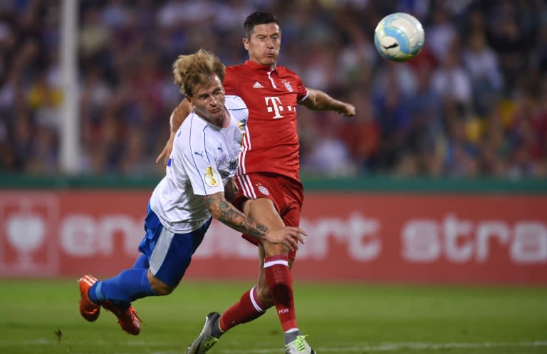 Jena's defender Rene Klingbeil (L) and Bayern Munich's Polish striker Robert Lewandowski vie for the ball during the German Cup first round football match between Bayern Munich and the German regional soccer team Werder Bremen