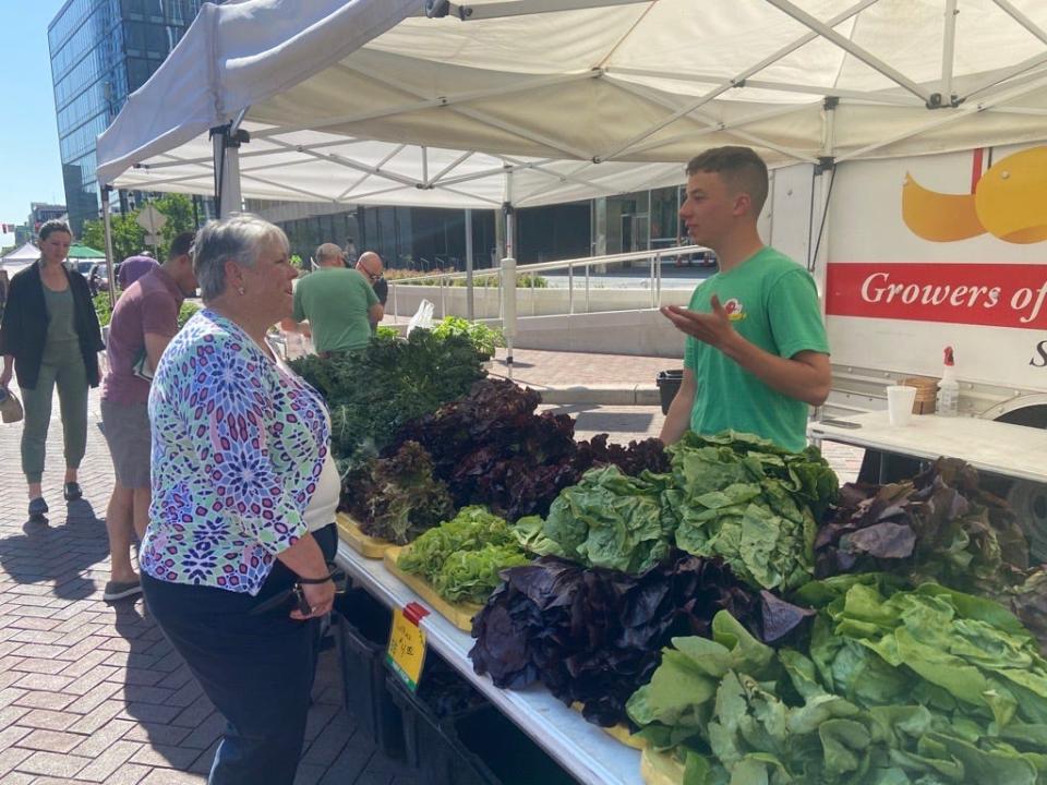 Thaddeus Goecker, 19, a farm worker on family-owned VanAntwerp Farm, talks with a customer at the Indianapolis Original Farmers’ Market on Market Street on May 31, 2023. He said in addition to having a stand in Seymour, Indiana, VanAntwerp's attends eight markets a week: one on Wednesdays, two on Thursdays and five on Saturdays.