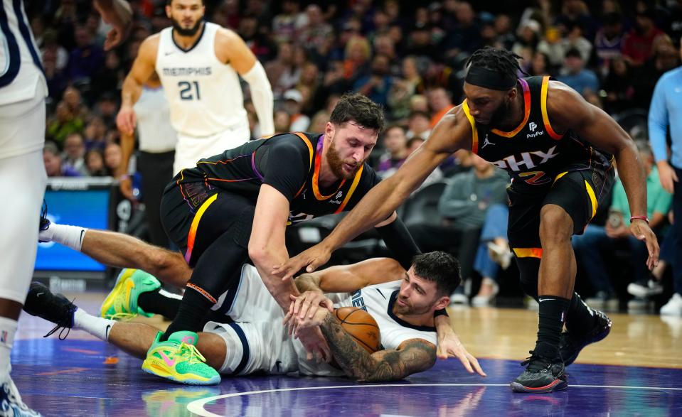 Grizzlies guard John Konchar (46) and Suns center Jusuf Nurkic (20) and Josh Okogie (2) fight for a loose ball during a game at the Footprint Center in Phoenix on Dec. 2, 2023.
