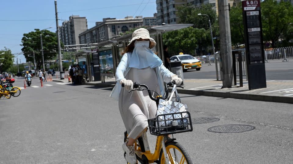 A woman wearing sun protective clothing rides a bike during hot weather conditions in Beijing on July 6. - Jade Gao/AFP/Getty Images