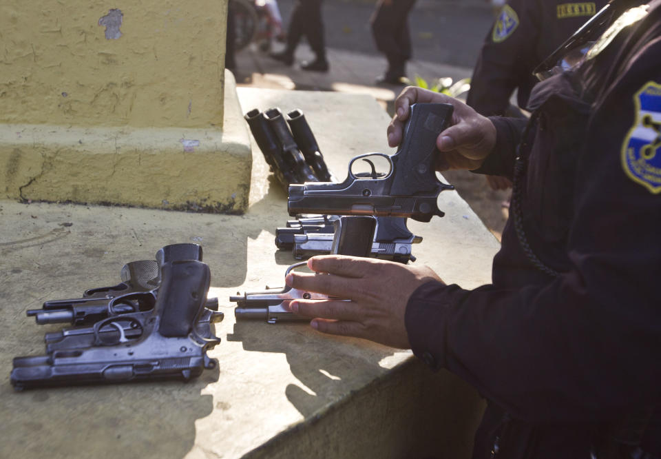 A police officer retakes his weapon after voting at a polling station during the presidential runoff election in San Salvador, El Salvador, Sunday, March 9, 2014. Salvadorans head to the polls Sunday to elect their next president in a runoff between former Marxist guerrilla Salvador Sanchez Ceren from the ruling Farabundo Marti National Liberation Front (FMLN), and former San Salvador Mayor Norman Quijano from the Nationalist Republican Alliance (ARENA). (AP Photo/Esteban Felix)