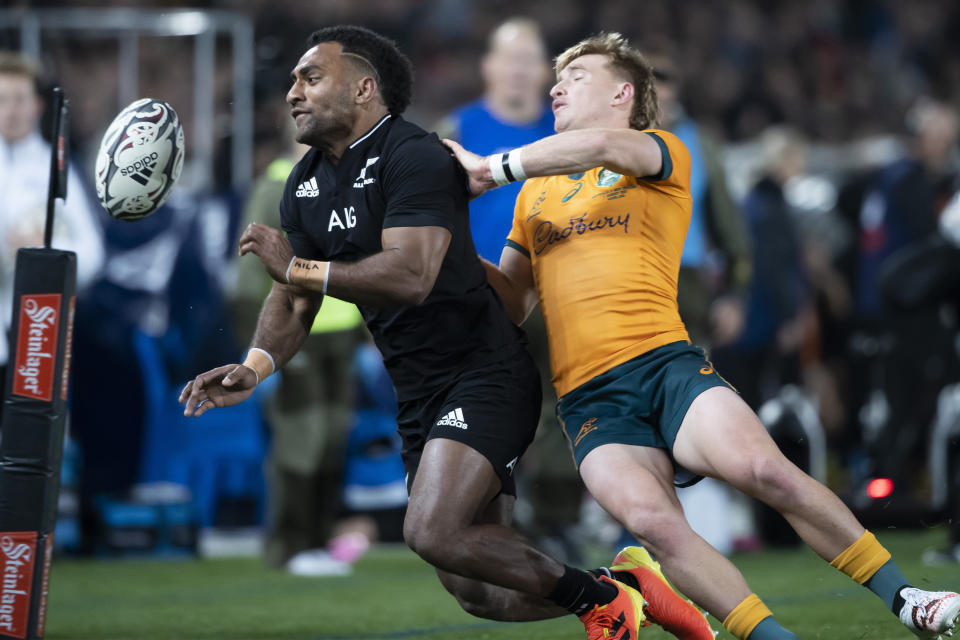 New Zealand's Sevu Reece, left, unloads the ball while pressured by Australia's Tate McDermott during their Bledisloe Cup rugby union test match at Eden Park in Auckland, New Zealand, Saturday, Aug. 7, 2021. (Brett Phibbs/Photosport via AP)