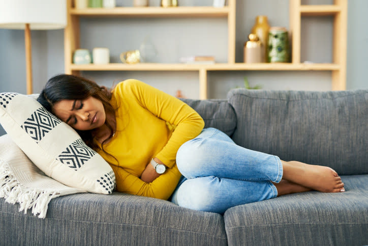 A person in discomfort lying on a couch