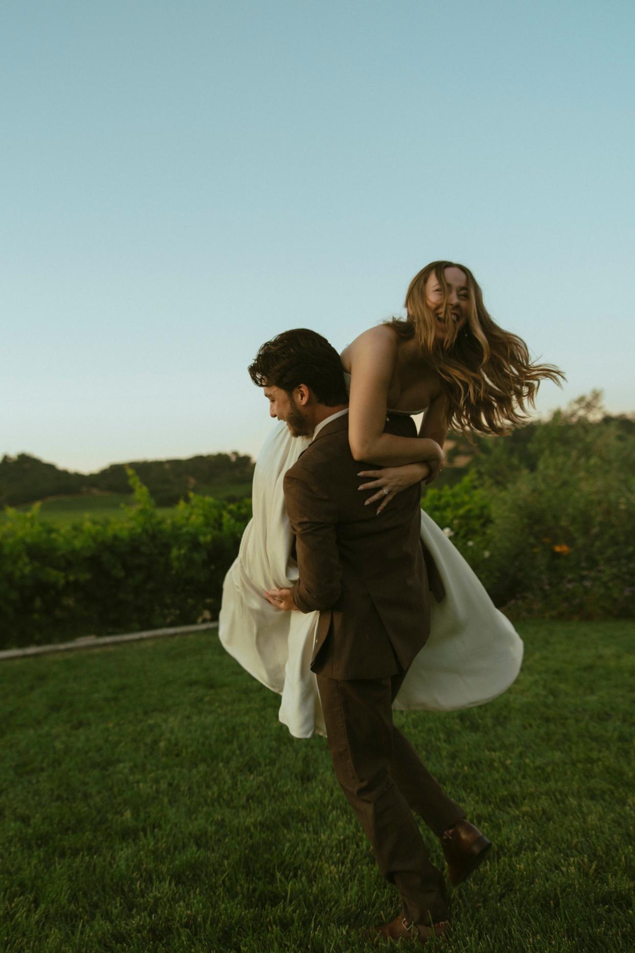 A groom holds his bride over her shoulder.