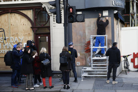 A worker tries to remove a new graffiti mural attributed to Banksy, opposite the French embassy in London, Britain January 25, 2016. REUTERS/Stefan Wermuth