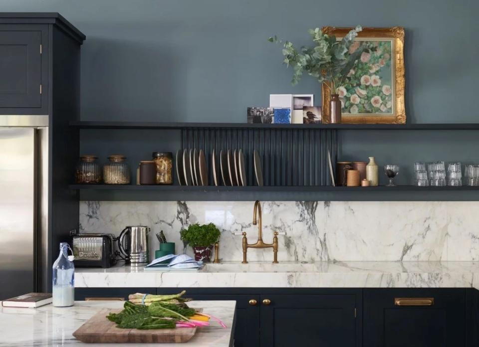 Kitchen cabinets with blue-green walls and blue-black cabinets with marble countertop.