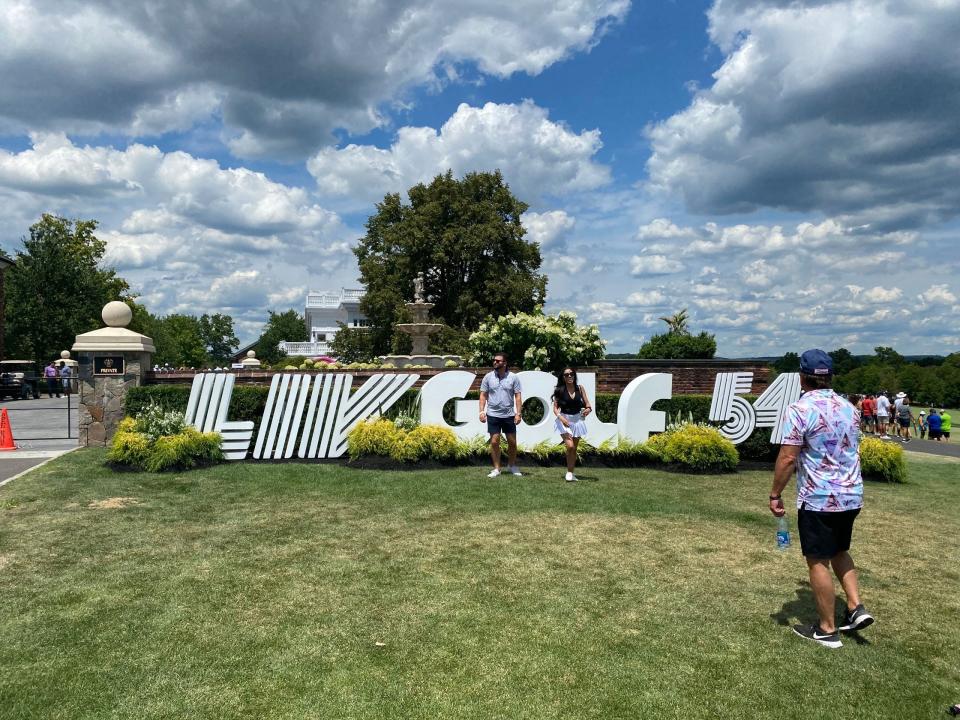 Fans take photos next to the LIV Golf logo.