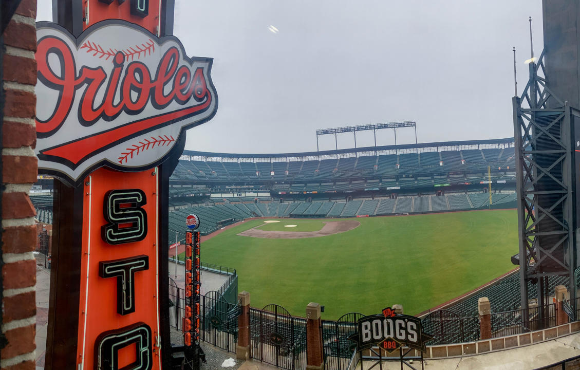 View of empty baseball stadium's field and seating with signs reading Orioles and Boog's BBQ in foreground.