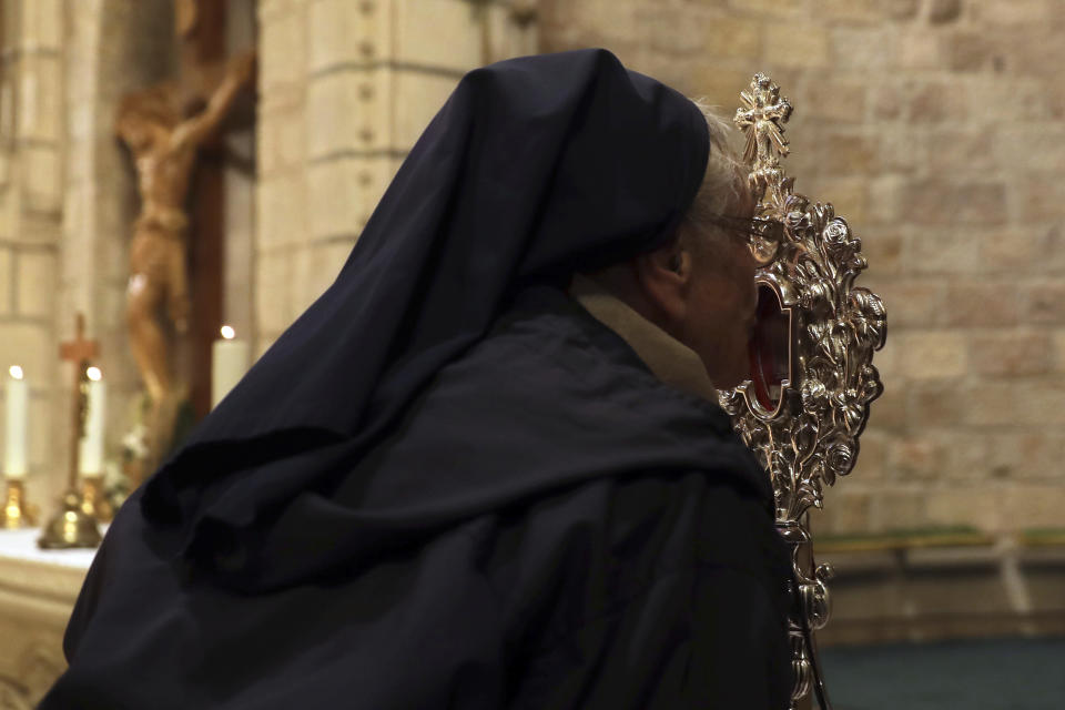 A Christian nun kisses a wooden relic believed to be from Jesus' manger at the Notre Dame church in Jerusalem, Friday, Nov. 29, 2019. Christians are celebrating the return to the Holy Land of a tiny wooden relic believed to be from Jesus' manger nearly 1,400 years after it was sent to Rome as a gift to the pope. (AP Photo/Mahmoud Illean)