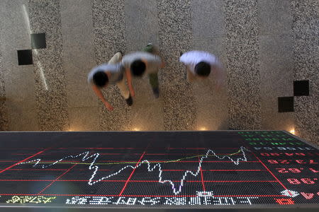 FILE PHOTO: People walk under an electronic board showing stock information at the Shanghai Stock Exchange in Lujiazui Financial Area before the visit of Britain's Chancellor of the Exchequer George Osborne in Shanghai, China, September 22, 2015. REUTERS/Aly Song