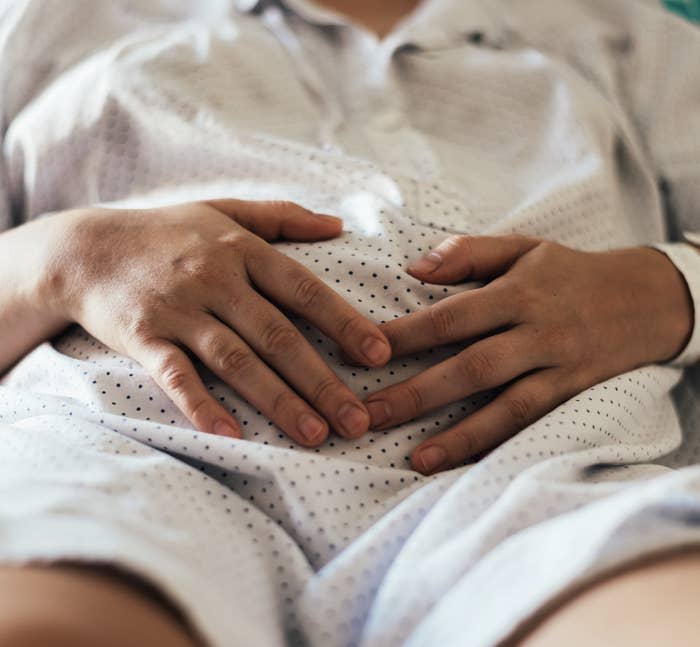 Pregnant person in a hospital bed cupping their belly