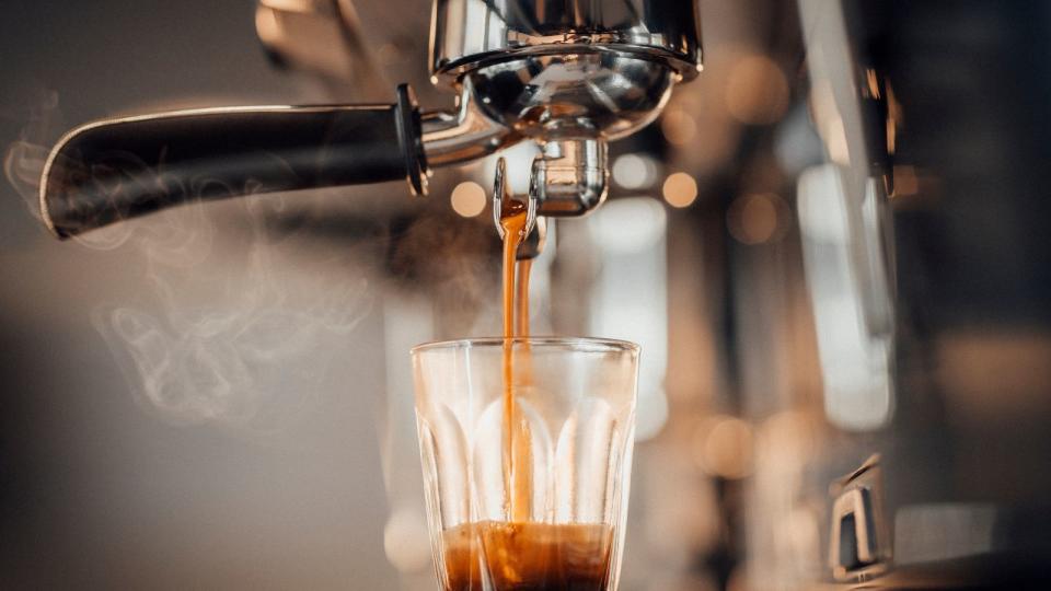 An espresso in a glass under the portafilter of an espresso machine