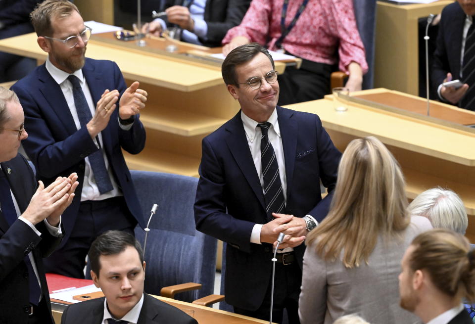 Moderate Party leader Ulf Kristersson, center, smiles after being elected as Sweden's new prime minister at the Parliament in Stockholm, Monday Oct. 17, 2022. The Swedish parliament on Monday elected Kristersson as prime minister at the head of a coalition that is being supported by a once radical far-right party. (Fredrik Sandberg/TT News Agency via AP)