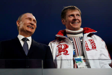 FILE PHOTO: Russian President Vladimir Putin (L) laughs with Russia's gold medallist bobsleigh athlete Alexander Zubkov during the closing ceremony for the 2014 Sochi Winter Olympics, February 23, 2014. REUTERS/Phil Noble/File Photo