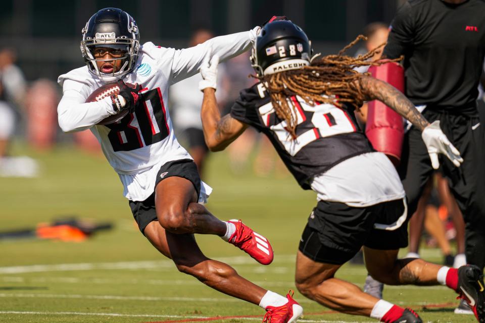 El receptor abierto de los Atlanta Falcons, Cameron Batson (80), corre contra el back defensivo Mike Ford (28) durante el campamento de entrenamiento en IBM Performance Field.