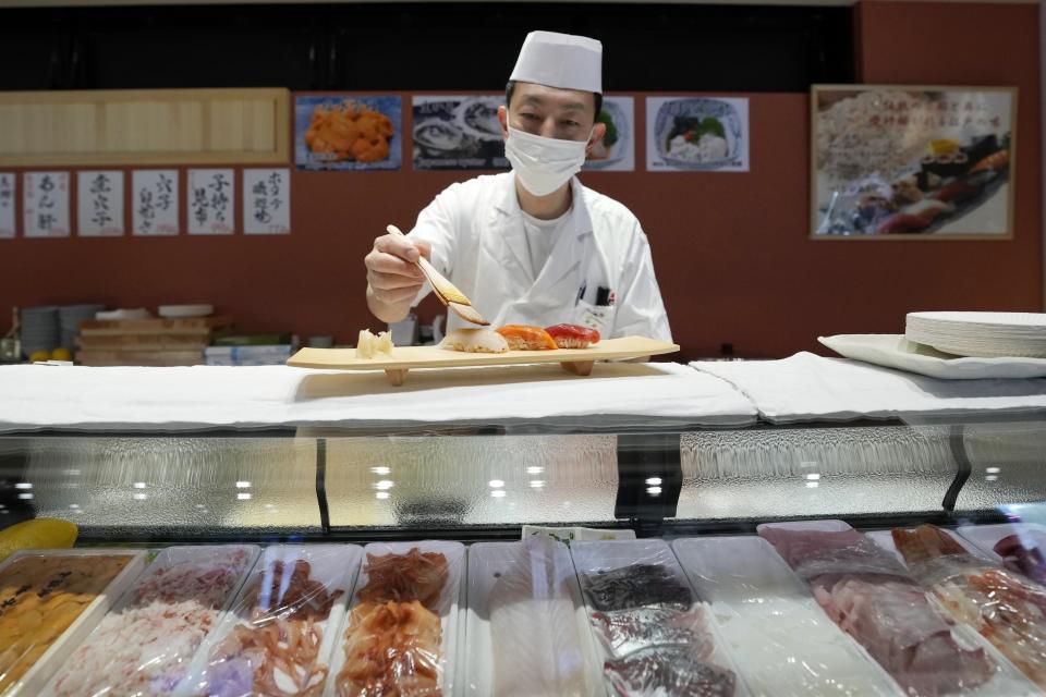 A sushi chef prepares a sushi plate at "Toyosu Senkyaku Banrai," an Edo Period-themed hot spring complex is seen on media preview event at Toyosu Market Monday, Jan. 29, 2024, in Tokyo. Japan's biggest fish market on Thursday opened a long-awaited outer section with Japanese-style seafood restaurants and a spa for relaxation, as the wholesale venue that has struggled since relocating from the beloved Tsukiji market seeks to lure more visitors. (AP Photo/Eugene Hoshiko)