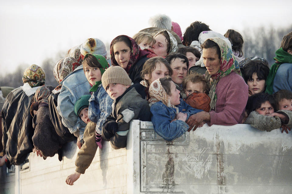 FILE- In this Monday, March 29, 1993 file picture evacuees from the besieged Muslim enclave of Srebrenica, packed on a truck en route to Tuzla, pass through Tojsici. Survivors of the genocide in the eastern Bosnian town of Srebrenica, mainly women, will on Saturday July 11, 2020, commemorate the 25th anniversary of the slaughter of their fathers and brothers, husbands and sons. At least 8,000 mostly Muslim men and boys were chased through woods in and around Srebrenica by Serb troops in what is considered the worst carnage of civilians in Europe since World War II. The slaughter was also the only atrocity of the brutal war that has been confirmed an act of genocide.(AP Photo/Michel Euler, File)