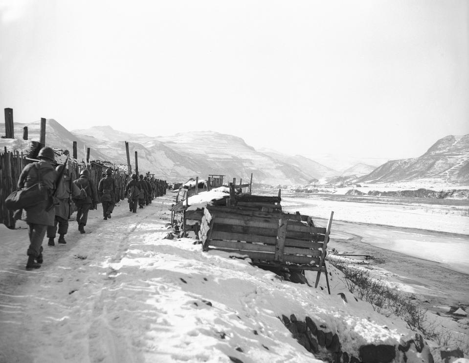 FILE - Americans of the Seventh Division's 17th Regimental Combat team march along the North Korean bank of the Yalu River, right, on Nov. 25, 1950, after reaching the border town of Hyesanjin to climax their daring drive north. Snow-covered hills of Manchuria loom over river at right. Gene Herrick, a retired Associated Press photographer who covered the Korean War and is known for his iconic images of Martin Luther King Jr., Rosa Parks and the civil rights movement, died Friday, April 12, 2024 at a nursing home in Rich Creek, Virginia. He was 97. (AP Photo/Gene Herrick)