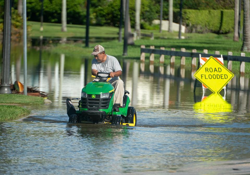 A man drives his lawnmower on North Flagler Drive during king tide flooding in West Palm Beach, Florida on September 30, 2023.