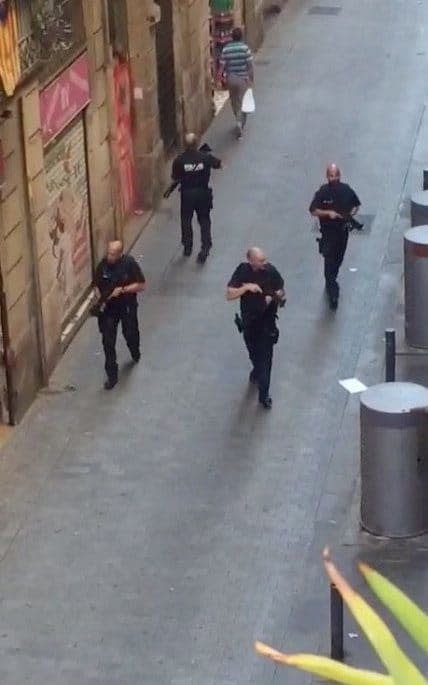 Armed police officers patrol an empty street after a van crashed into pedestrians near the Las Ramblas avenue in central Barcelona - Credit:  REUTERS