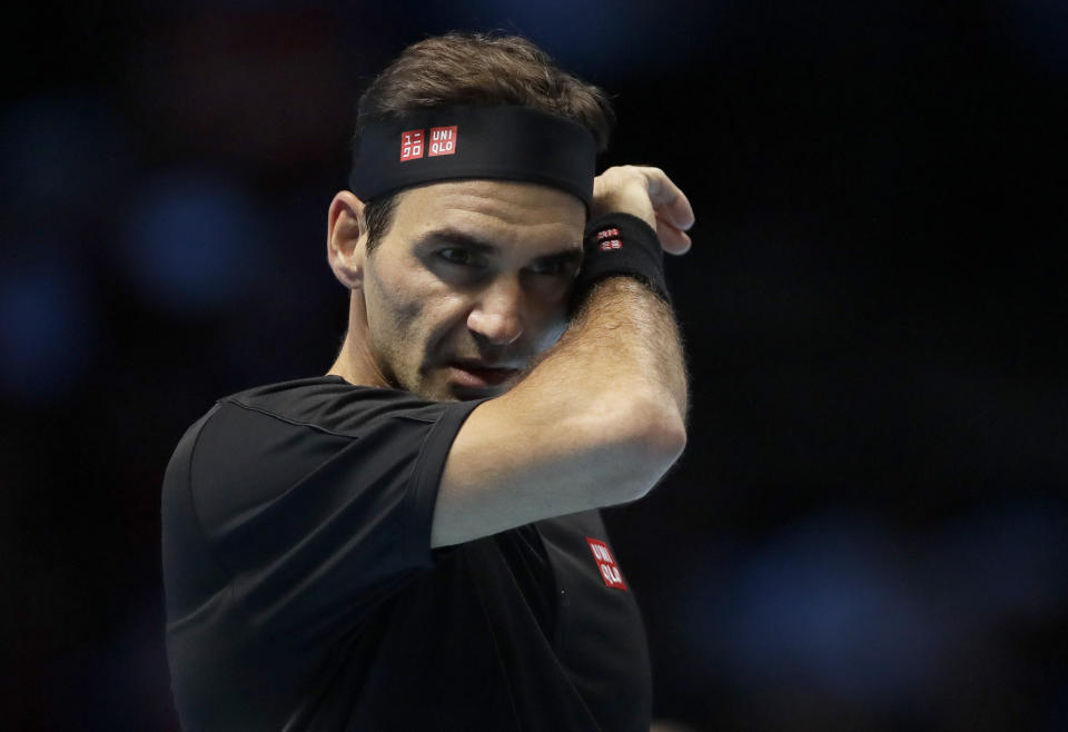 Roger Federer of Switzerland wipes his face after he plays a return to Stefanos Tsitsipas of Greece during their ATP World Tour Finals semifinal tennis match at the O2 Arena in London, Saturday, Nov. 16, 2019. (AP Photo/Kirsty Wigglesworth)