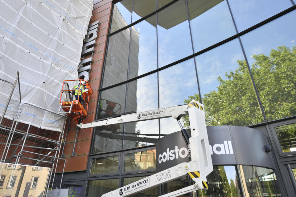 Contractors use an aerial platform outside Bristol music venue Colston Hall to remove the name of slave trader Edward Colston from its signage, in Bristol, England, Monday, June 15, 2020. The removal of the signage comes just over a week after a statue of Colston was hauled from its plinth by protesters in the English port city of Bristol and dumped in the Bristol harbour, during an anti-racism protest. (Ben Birchall/PA via AP)