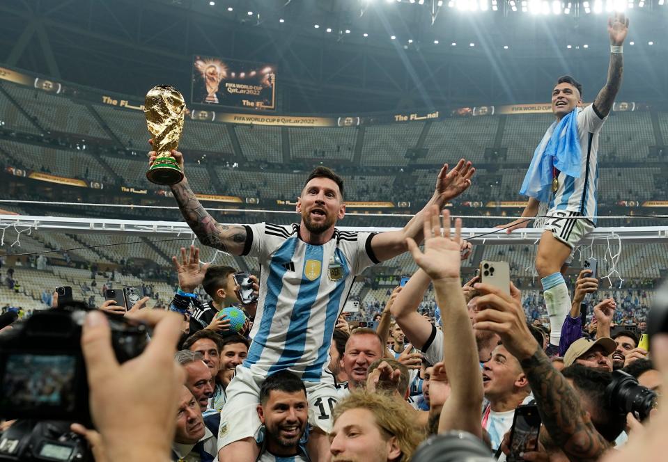 Argentina's Lionel Messi celebrates with the trophy in front of the fans after winning the World Cup final soccer match between Argentina and France at the Lusail Stadium in Lusail, Qatar, Sunday, Dec. 18, 2022. Argentina won 4-2 in a penalty shootout after the match ended tied 3-3. (AP Photo/Martin Meissner)