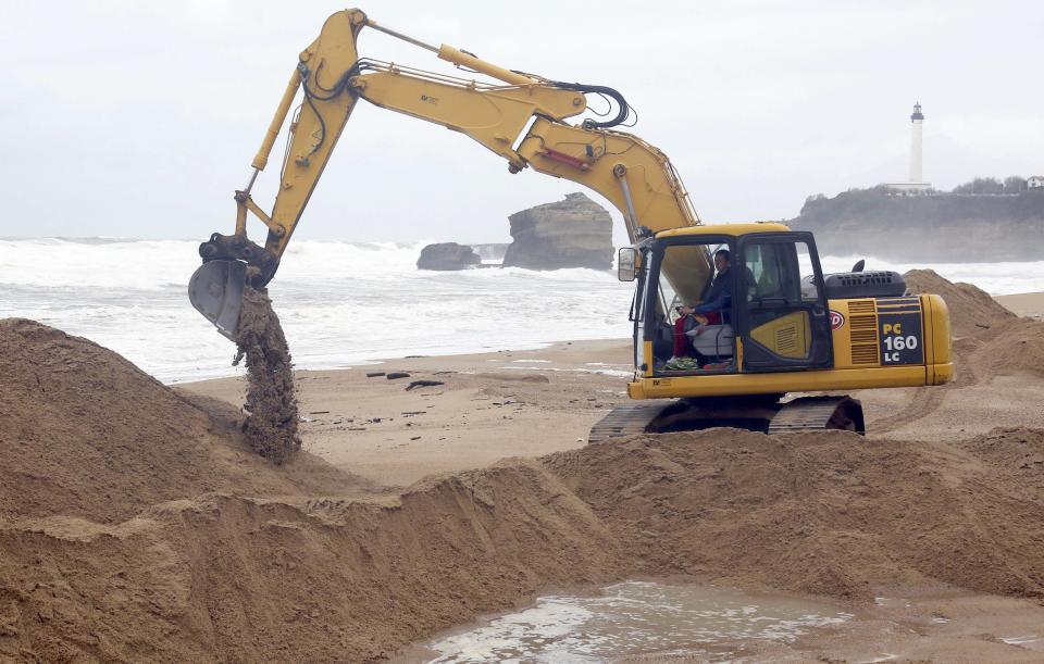 Una retroexcavadora mueve la arena para crear una duna que proteja la costa de la erosión durante una tormenta, cerca de El Casino, en Biarritz.