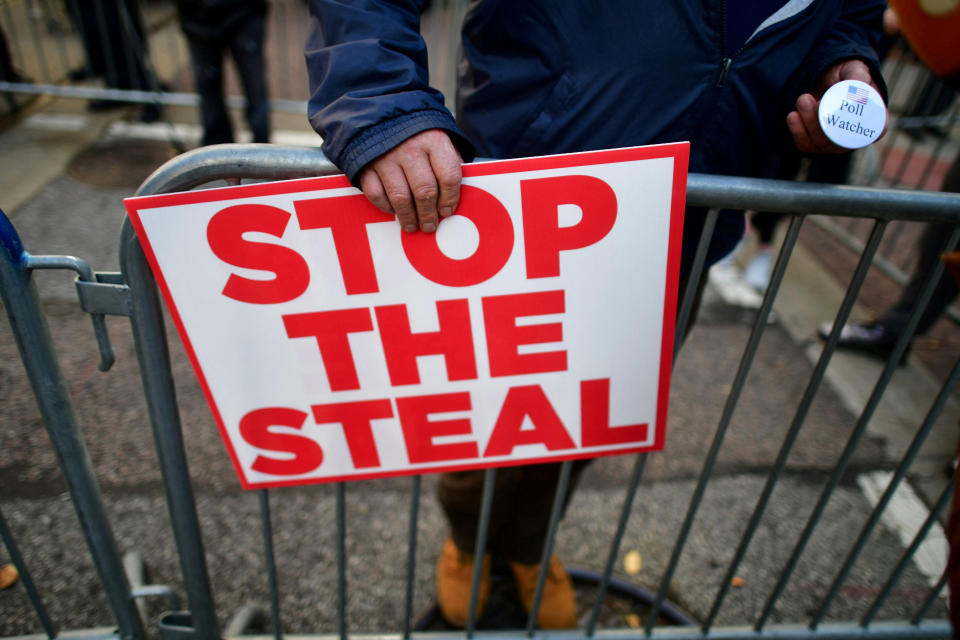 A supporter of President Donald Trump holds a sign saying STOP THE STEAL and a pin saying Poll Watcher. 