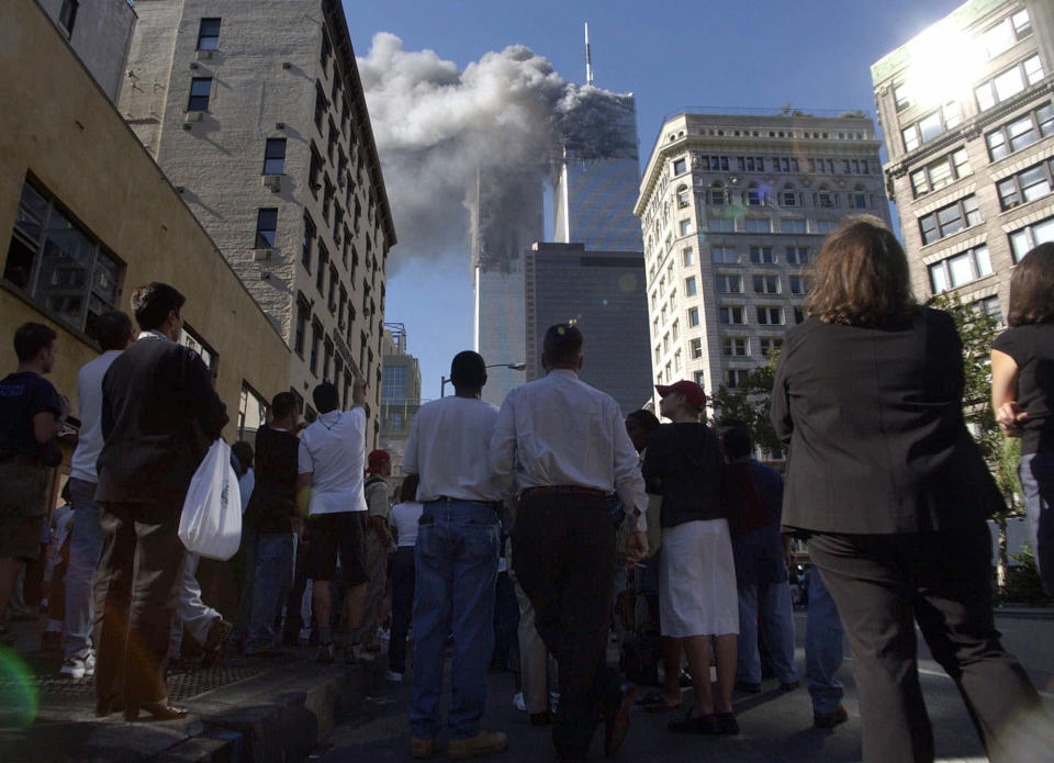 FILE - Pedestrians in lower Manhattan watch smoke billow from New York's World Trade Center on Tuesday, Sept. 11, 2001. Just this century, the 9/11 attacks in 2001, as the US launched a “shock and awe″ war on Saddam Hussein’s Iraq two years later, March 2020 as the pandemic began to sweep across the globe, killing millions and upending everything in its path, and most recently when Russia invaded Ukraine on February 24, 2022. The latter brought ruinous war back to Europe’s heartland. (AP Photo/Amy Sancetta, File)