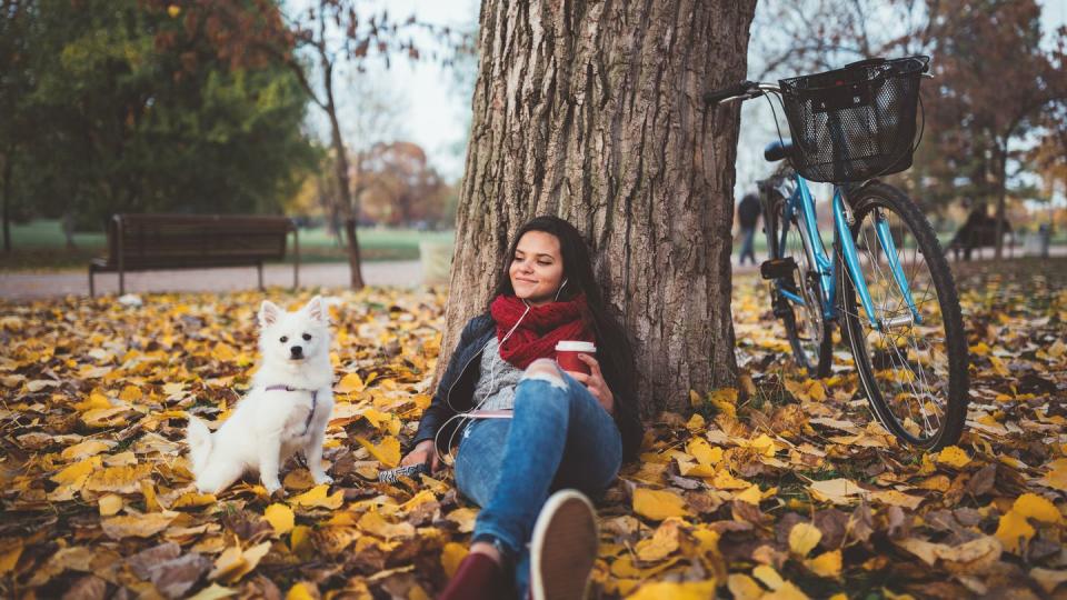 girl with her dog drinking coffee in the park