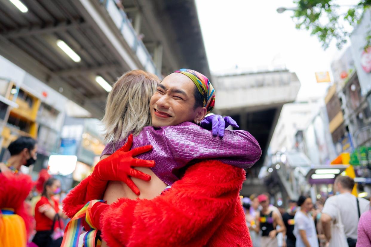 Happy Asian couple having fun in the street LGBTQ pride parade.