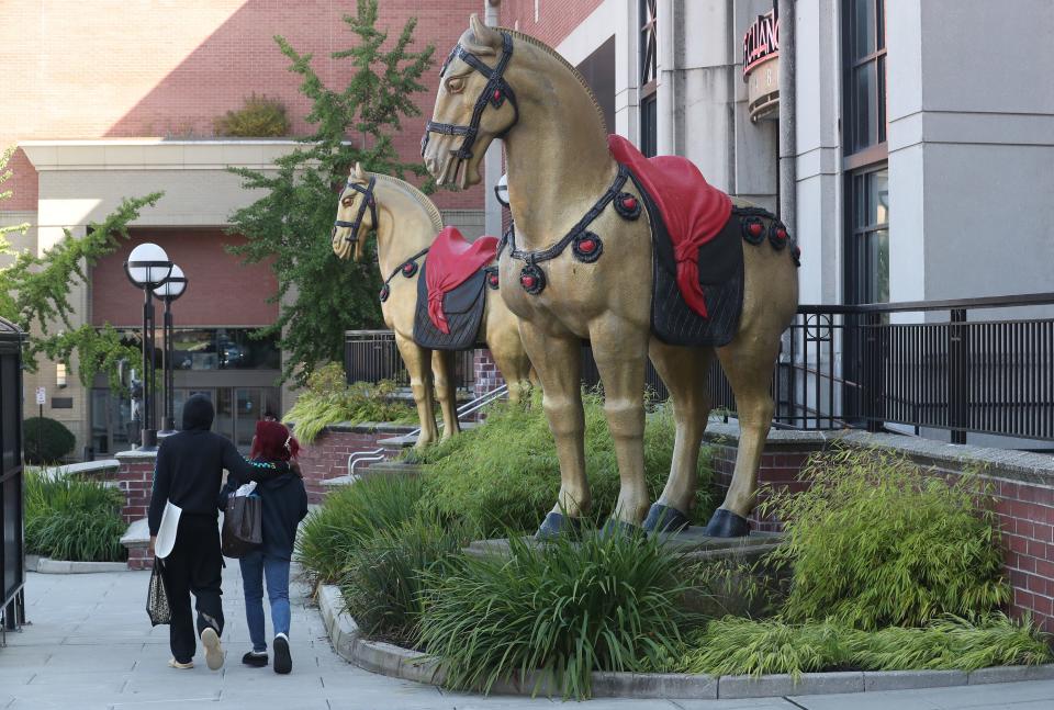 People on Westchester Avenue walk by the giant horses outside PF Chang's at The Westchester Mall in White Plains Sept. 27, 2023. The majestic 11 ft. tall horses grace the entrance to many PF Chang's restaurants. The horses stand guard as a symbol of strength.