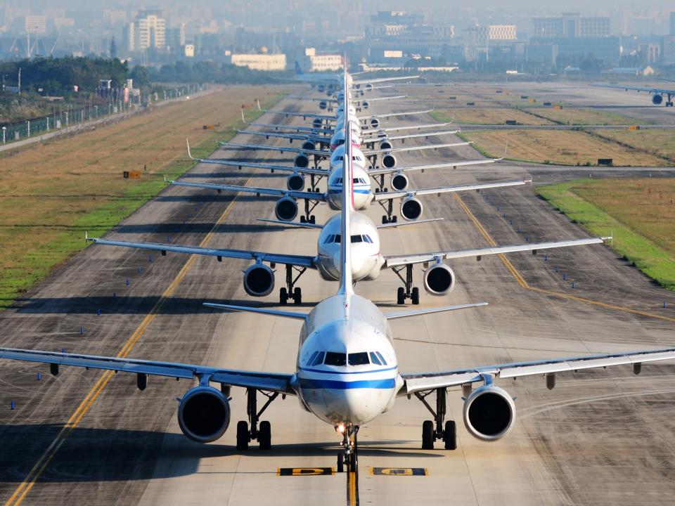 A line of airplanes on the runway waiting to take off.