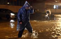 A man walks along a flooded street in Sochi, September 24, 2013. Regional authorities have declared a state of emergency in the area around Sochi because of flooding and mudslides less than five months before the Russian city hosts the Winter Olympics. Picture taken September 24, 2013. REUTERS/Maxim Shemetov (RUSSIA - Tags: ENVIRONMENT SPORT OLYMPICS)