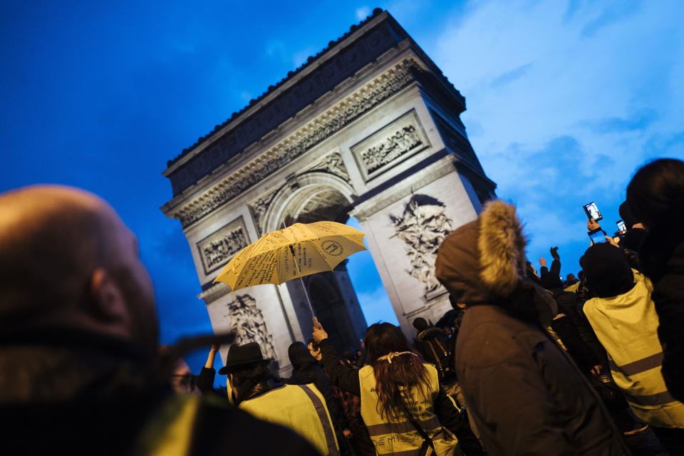 Demonstrators wearing yellow vests stand near the Arc de Triomphe as they gather in Paris, Saturday, Dec. 22, 2018. France's yellow vest protesters, who have brought chaos to Paris over the past few weeks with their economic demands, demonstrated in sharply reduced numbers Saturday at the start of the Christmas and New Year holidays. (AP Photo/Kamil Zihnioglu)